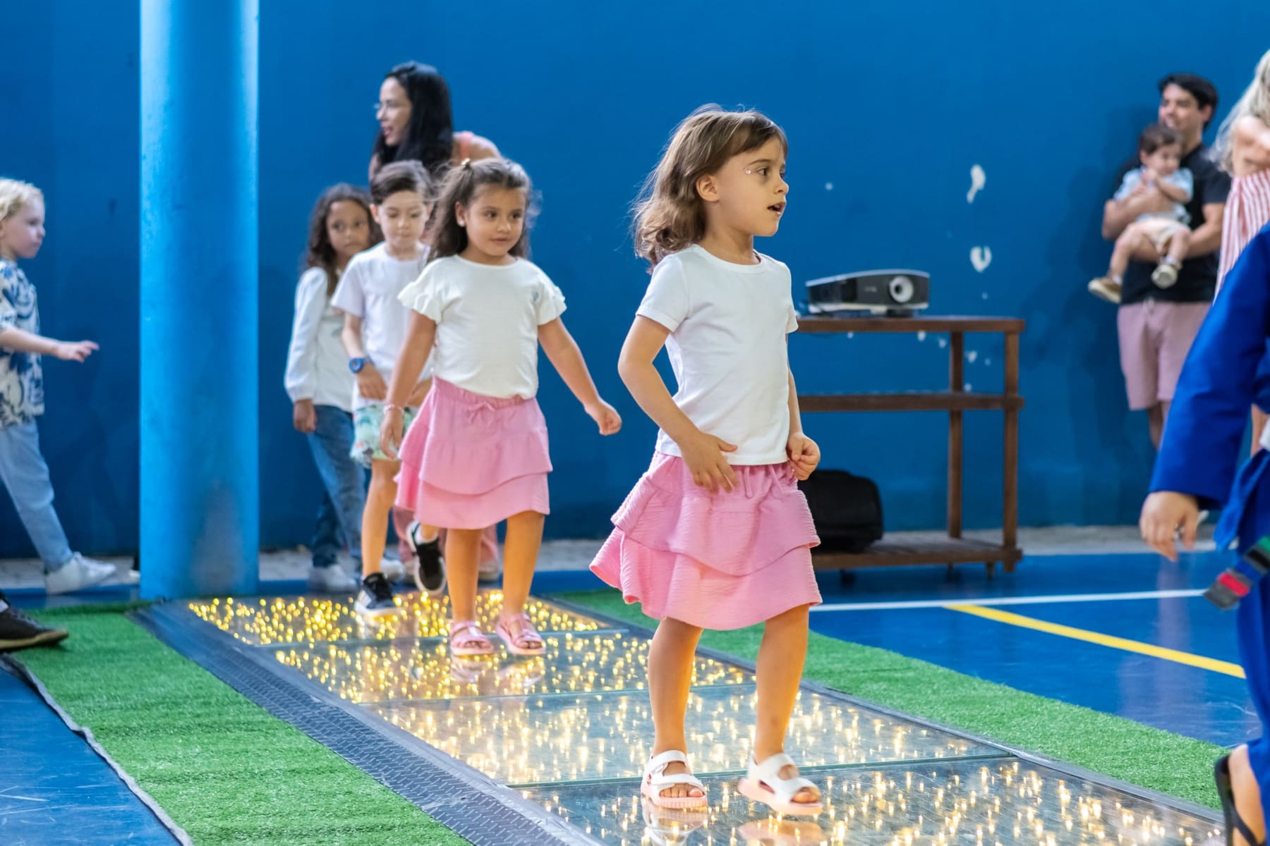 Crianças caminhando sobre uma passarela iluminada
